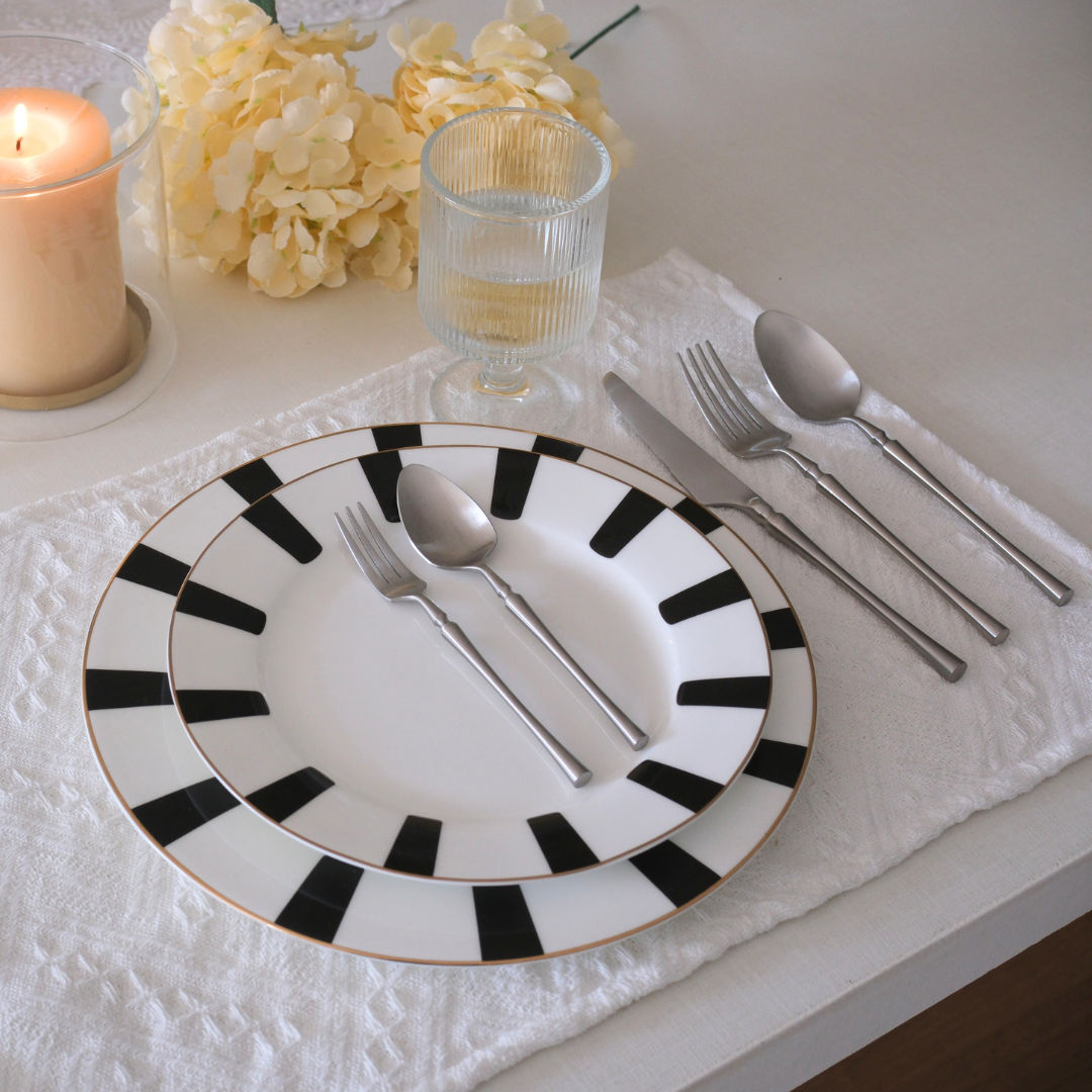 5 Pc Silver Cutlery Set placed on white textured runner with water glass and Hurricane