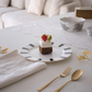 Delicate dessert on a plate with gold cutlery and white napkin on a table.