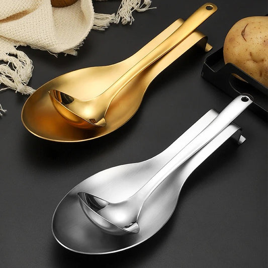 Two stainless steel spoon rests in gold and silver finishes, one displayed above the other, with a potato and a napkin in the background.