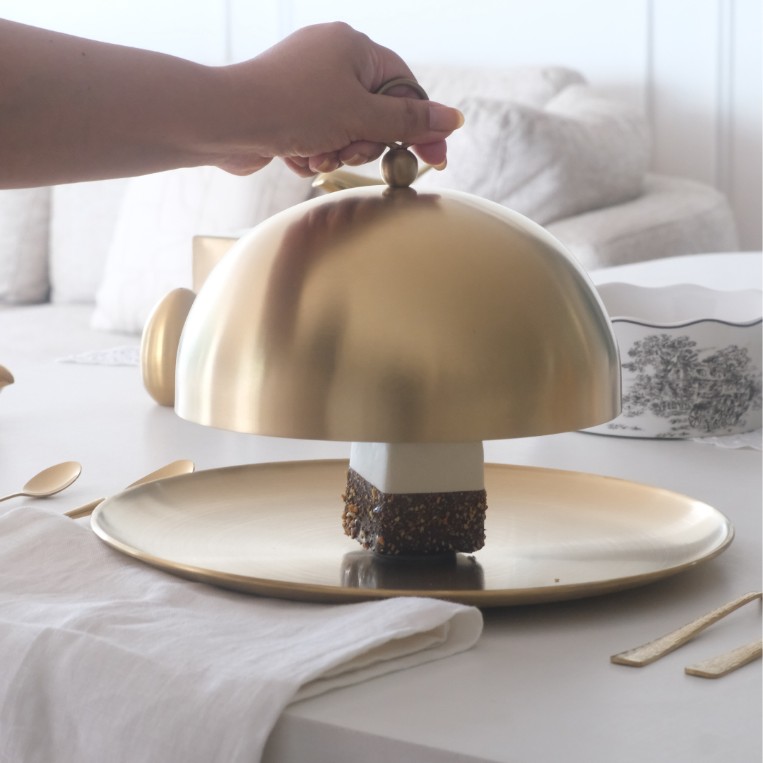 Gold cake stand with a piece of cake on a table.