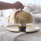 Gold cake stand with a piece of cake on a table.
