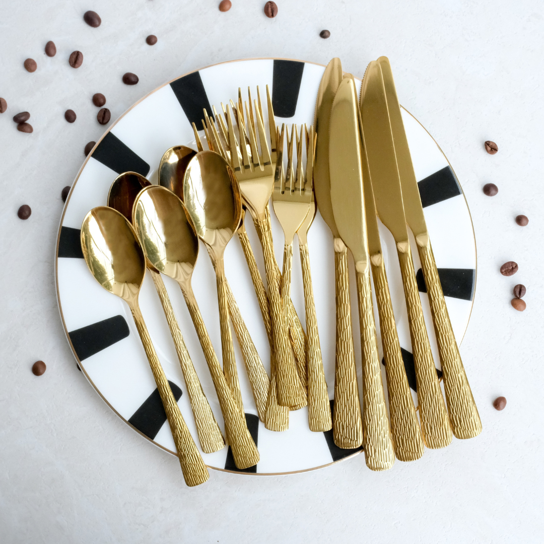 A 18 Pc Cutlery Set placed on a black & white plate with coffee beans around it