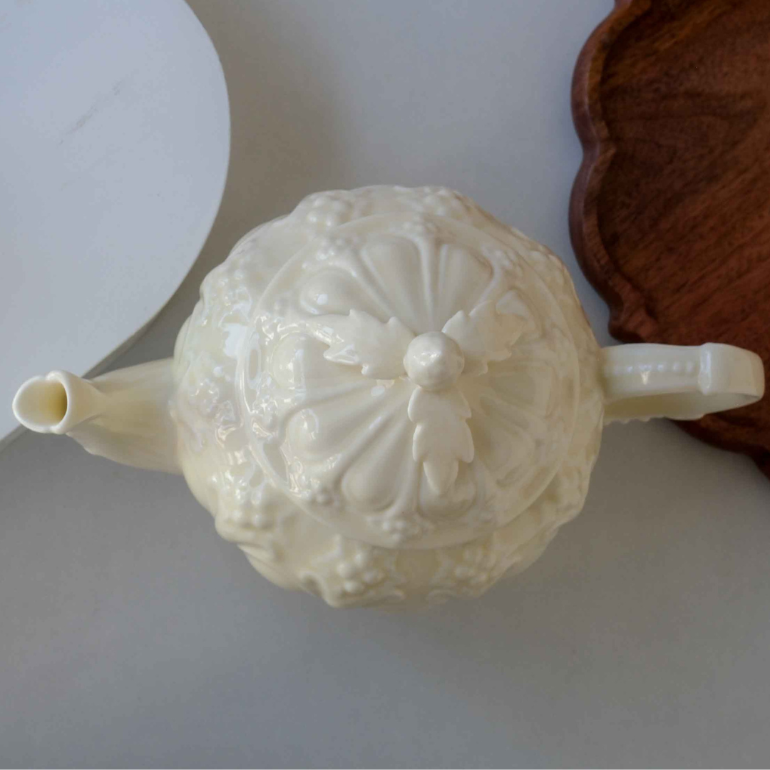 Off-white Victorian style porcelain tea pot featuring embossed detailing and decorative floral lid.