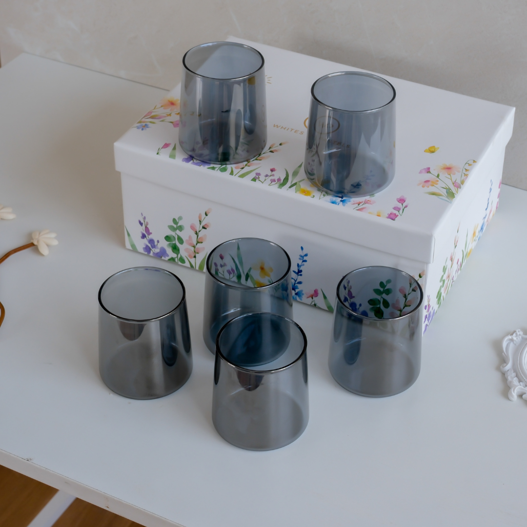 Top view of six black glass tumblers arranged in a protective gift box