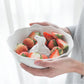 A white porcelain bowl with a polar bear embellishment, filled with fresh strawberries, held in a person's hands.