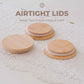 Three round bamboo airtight snack lids with white inner liners are arranged on a white textured doily. Text at the top reads 'AIRTIGHT LIDS' and 'Keeps Your Snacks Crispy & Fresh'.