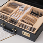 A black faux-leather briefcase-style storage box with complete set of silver cutlery consisting of Spoons, Forks and Dinner Knives resting on a white table runner in a home setting