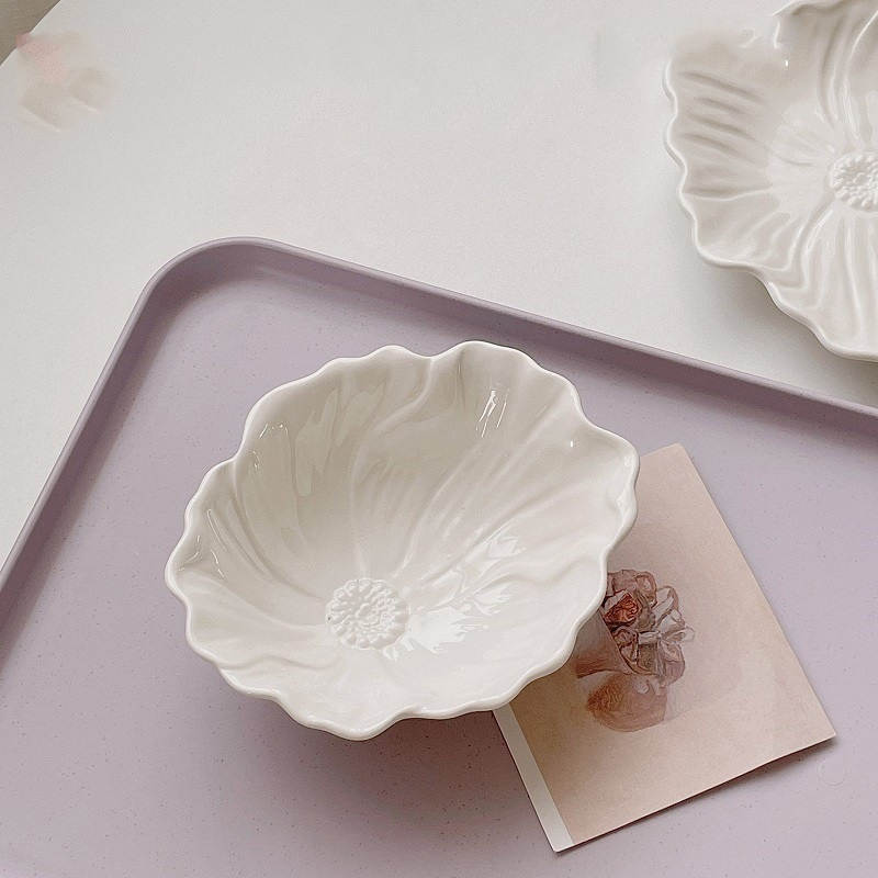 Two white porcelain dessert bowls with embossed flower patterns on a pink tray, one of the bowls contains a note card.
